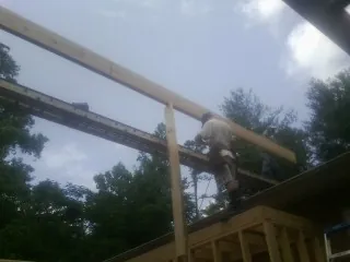 Carpenter setting a ridge beam over a new addition frame — Ice Dam Removal by Roofing Brothers in Jerusalem