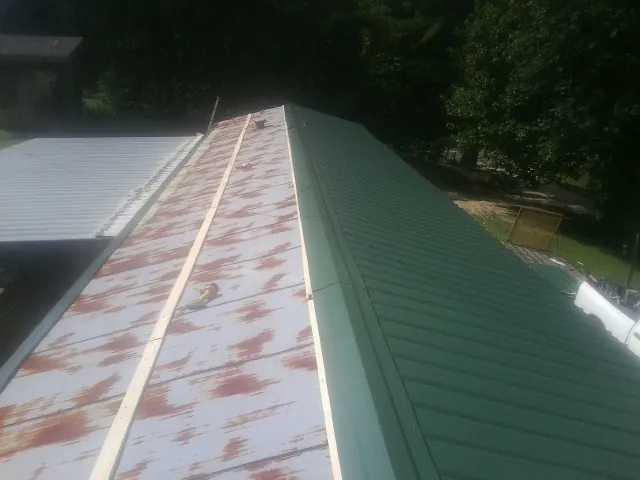 Old rusted panels beside newly installed green metal roofing — Wind Damage Roof Repair by Roofing Brothers in Jerusalem
