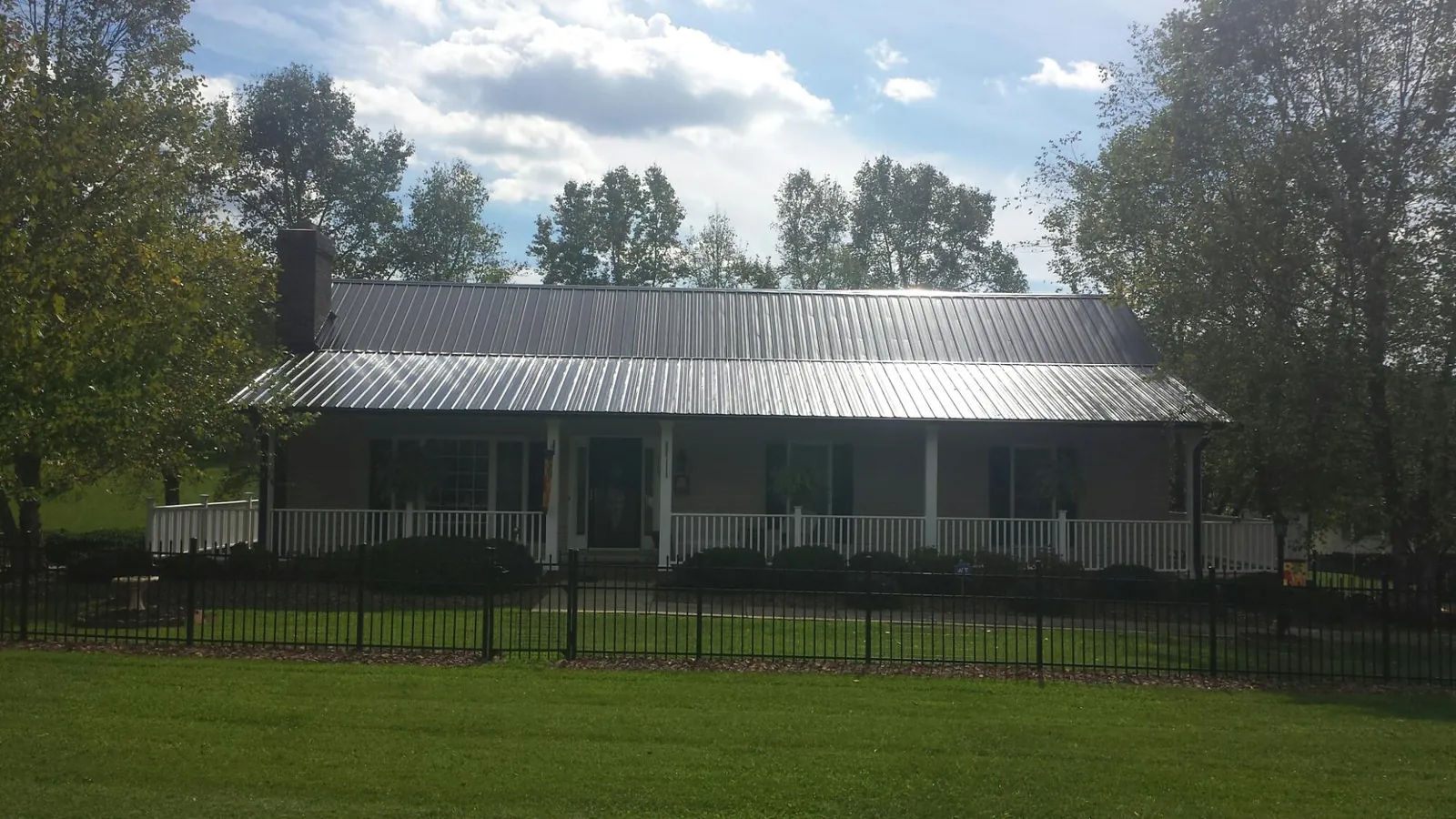 Gray metal roof on a brick ranch with a full width front porch — Gutter Guard Installation work by our crew in Jerusalem
