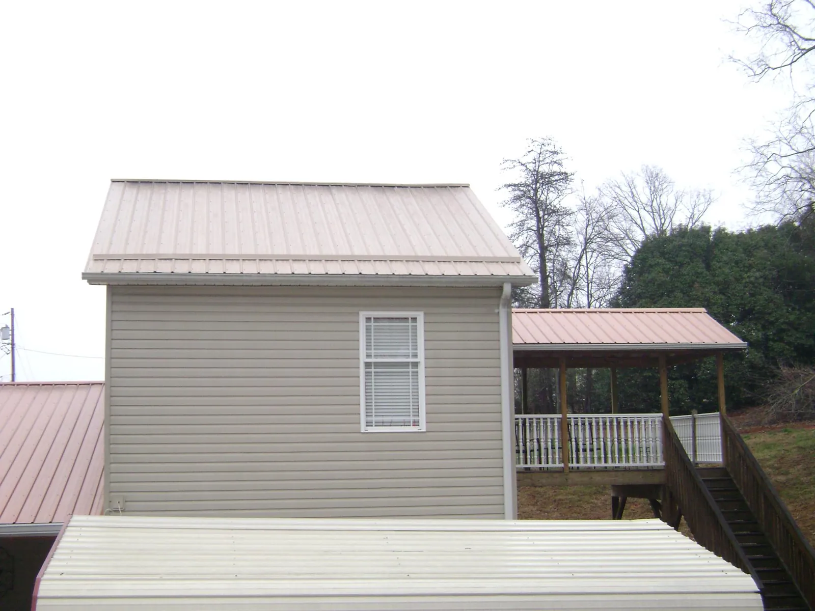 Tan metal roofs on a two story addition and attached porch, from a Roof Replacement job in Jerusalem